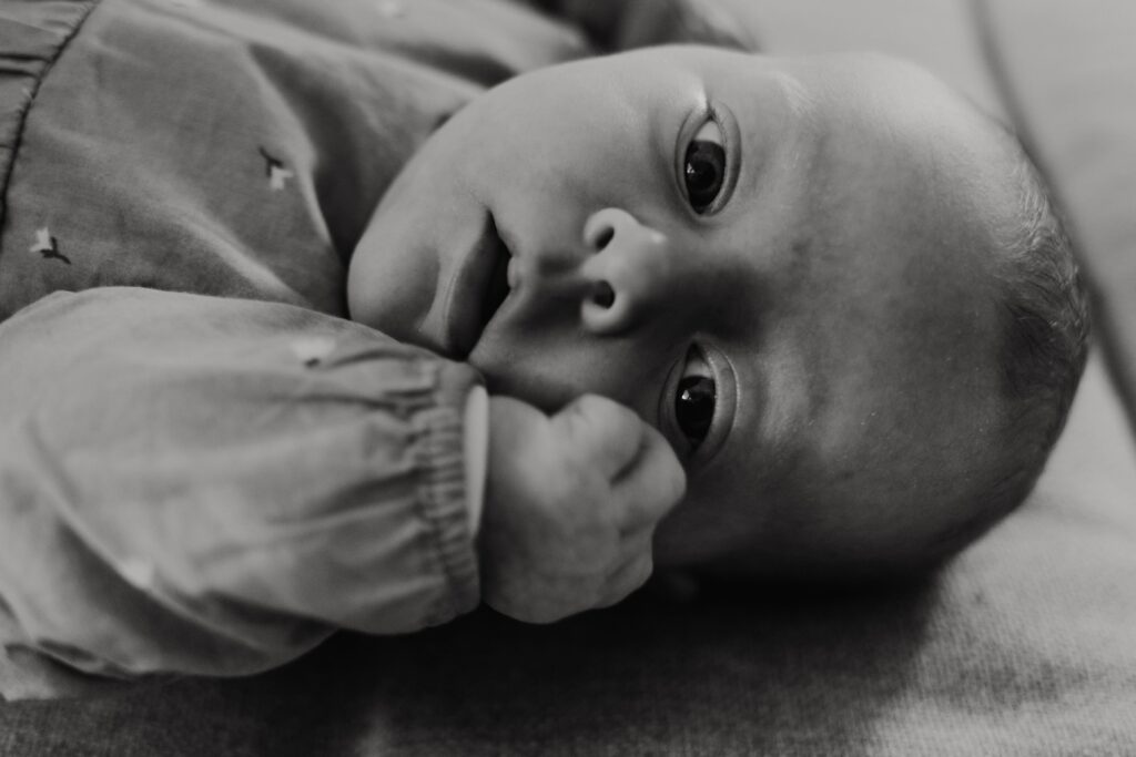 baby liegt auf dem sofa und schaut in die kamera während eines babyshootings in sinsheim