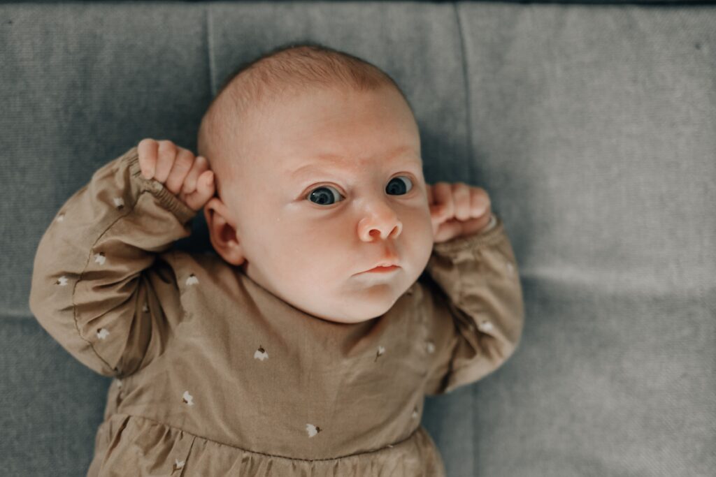 baby liegt auf dem sofa und schaut in die kamera während eines babyshootings in sinsheim