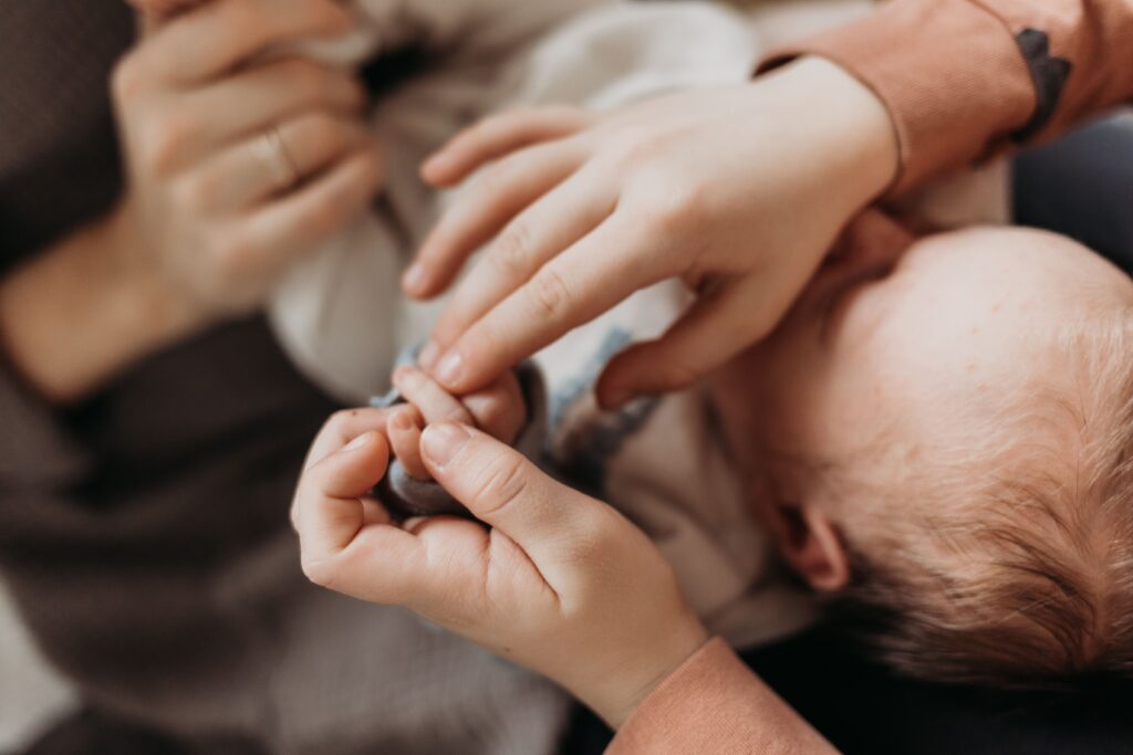 haende von mama und grossem bruder halten die babyhaende fest