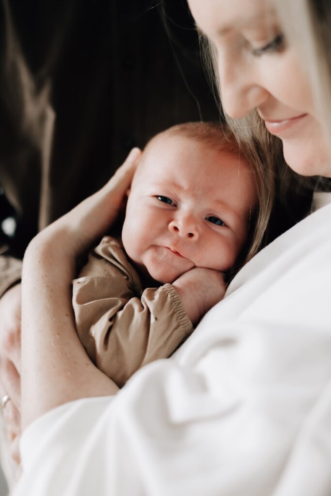 baby liegt auf dem arm seiner mutter und schaut in die kamera bei einem fotoshooting