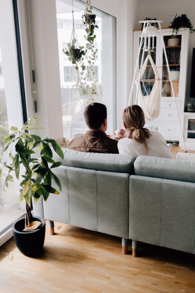 junge eltern sitzen mit baby auf dem sofa