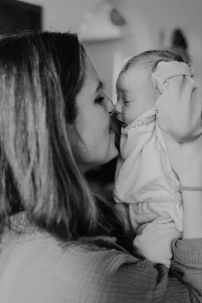 mama kuesst baby während sie es hochnimmt bei einem fotoshooting