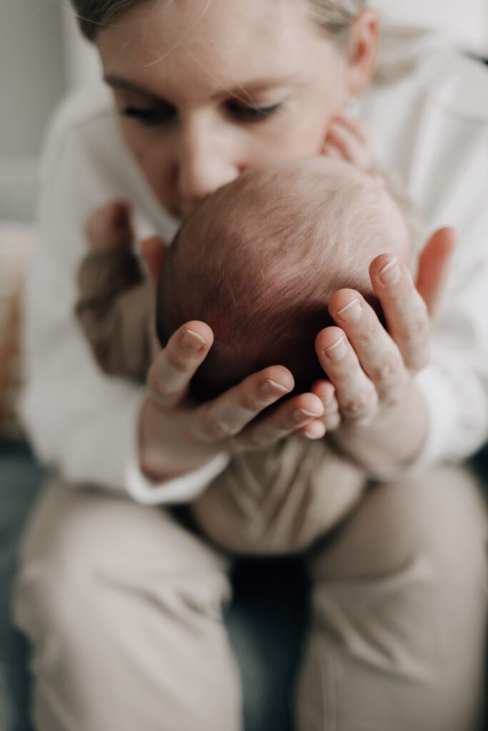 mama haelt ihr baby in den haenden und kuesst es