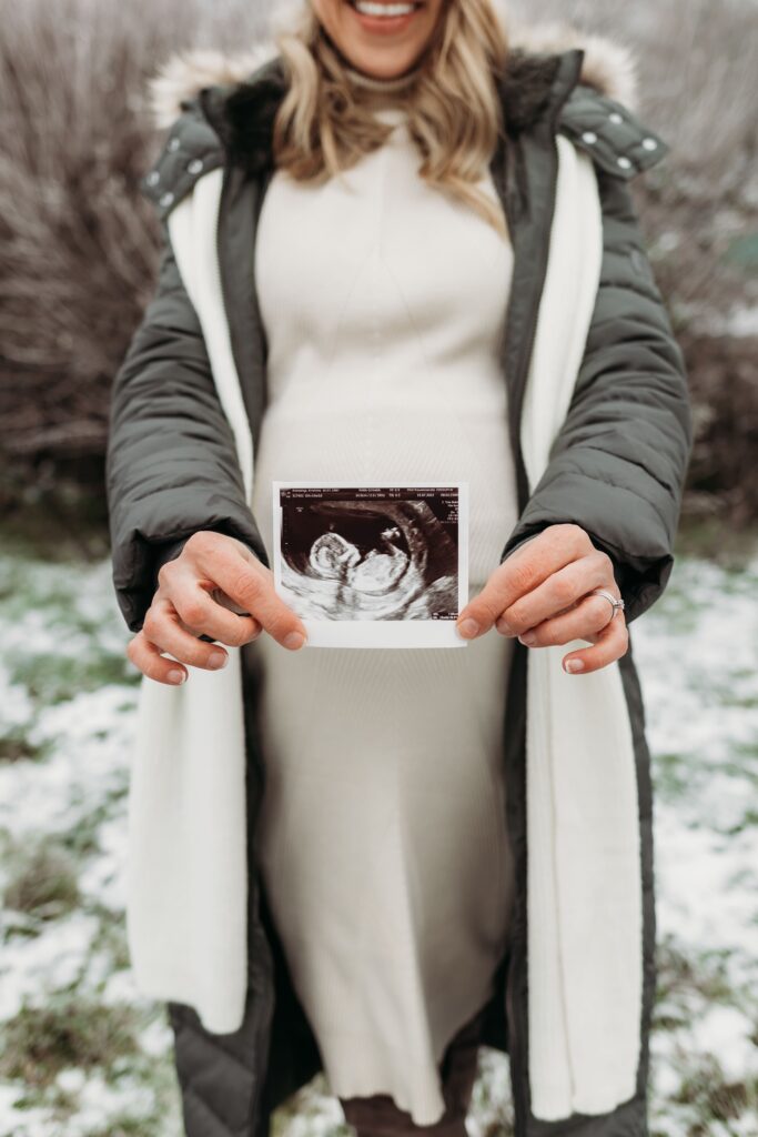 ultraschallbild wird in die kamera gehalten bei babybauchshooting