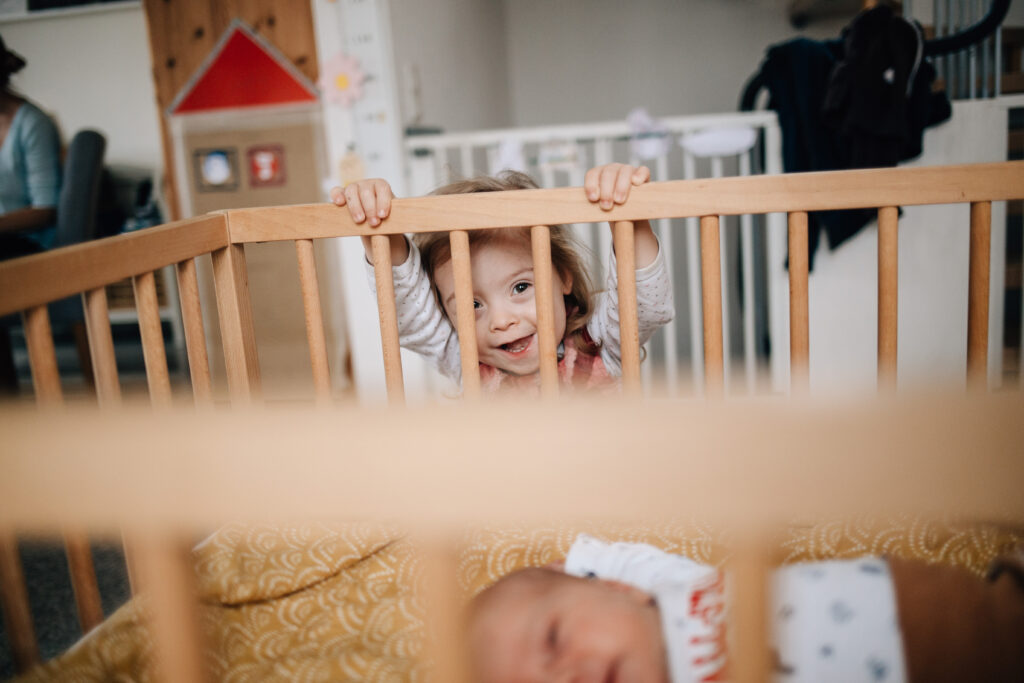 lachendes kind schaut in babybett hinein