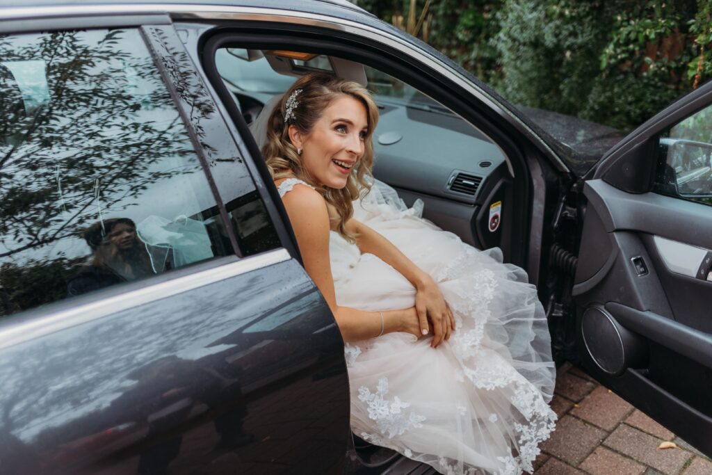 braut steigt aus dem auto auf dem weg zu ihrer hochzeit