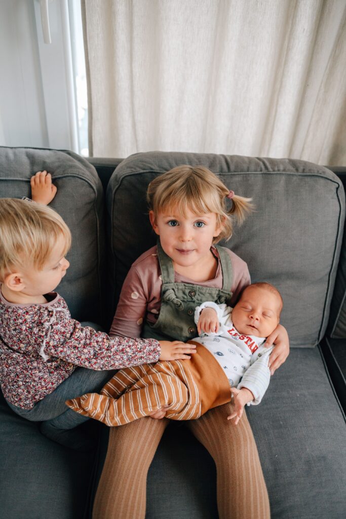 kinder halten baby auf dem arm und sitzen auf dem sofa