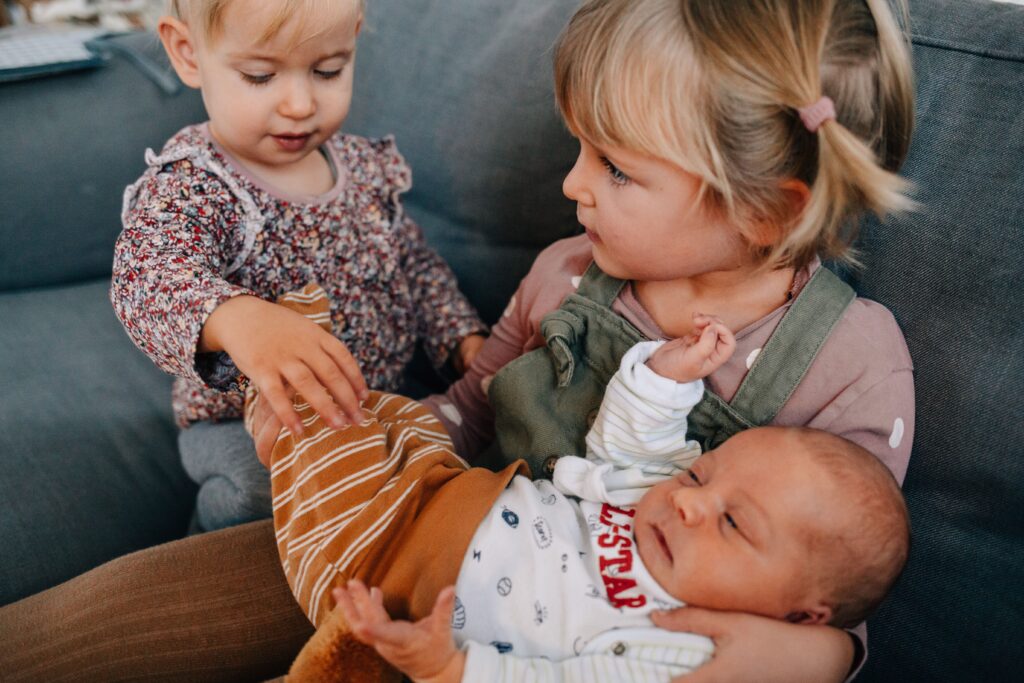 kinder halten baby auf dem arm und sitzen auf dem sofa