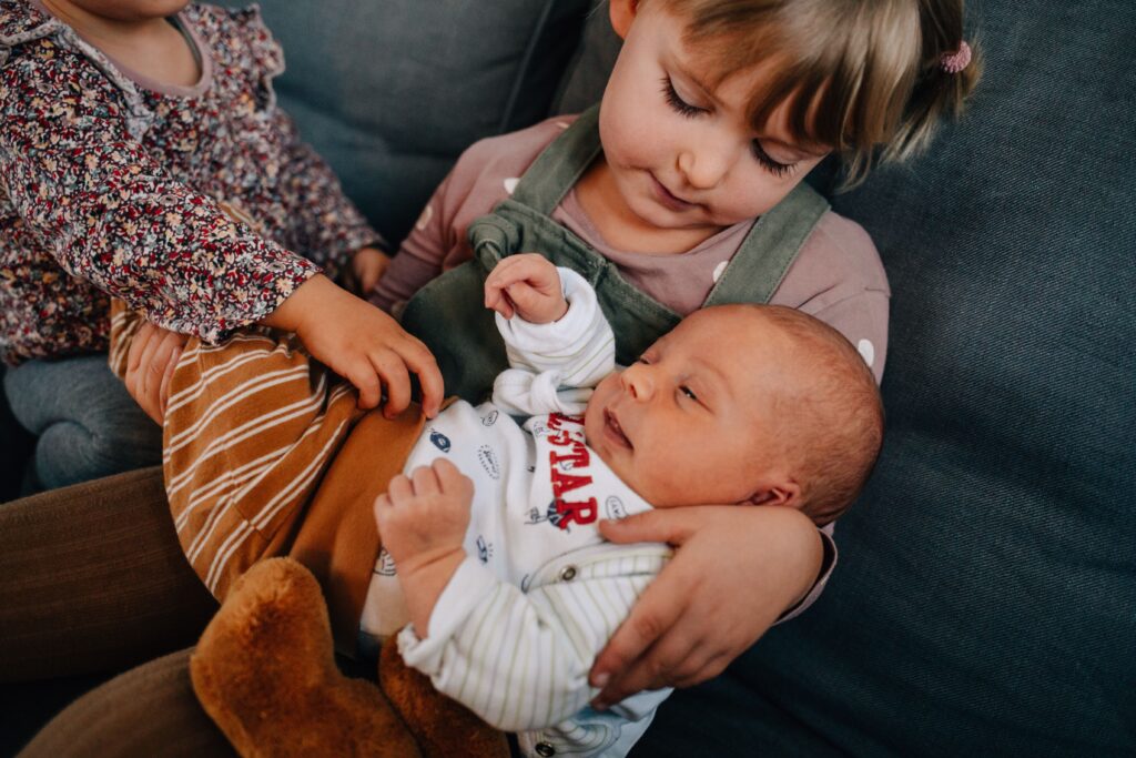 kinder halten baby auf dem arm und sitzen auf dem sofa