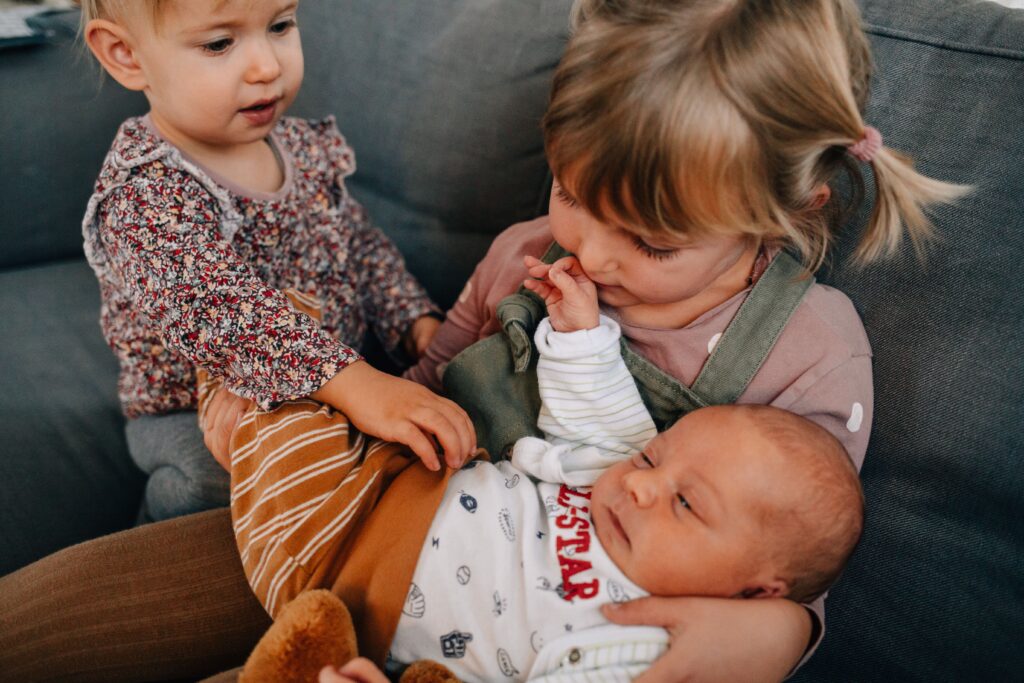 kinder halten baby auf dem arm und sitzen auf dem sofa