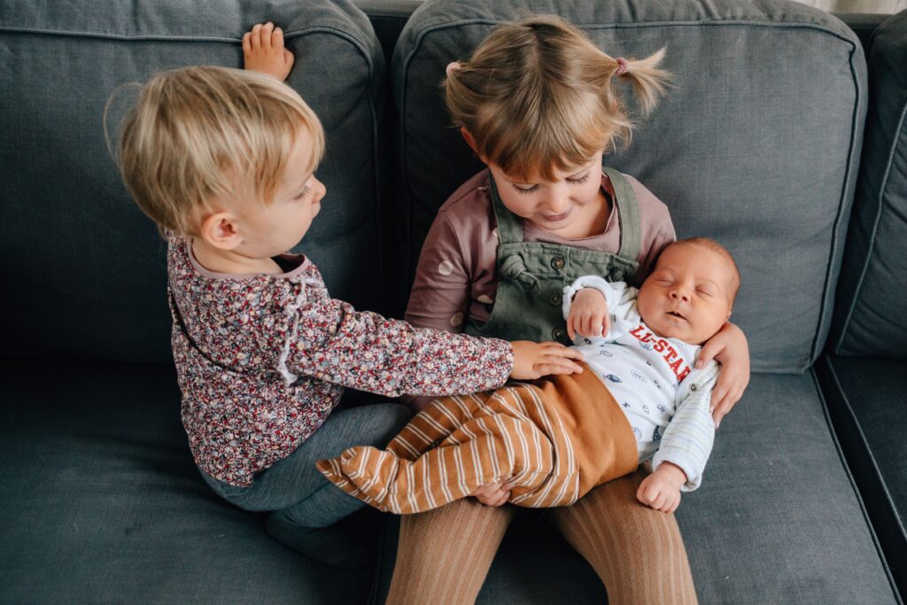 kinder halten baby auf dem arm und sitzen auf dem sofa