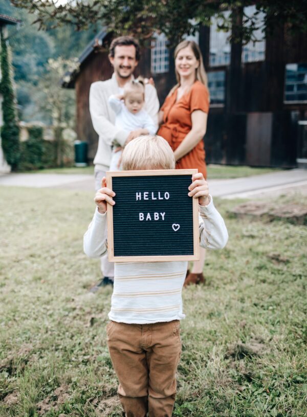 kind haelt baby schild hoch bei babybauchshooting mit fotografin in sinsheim