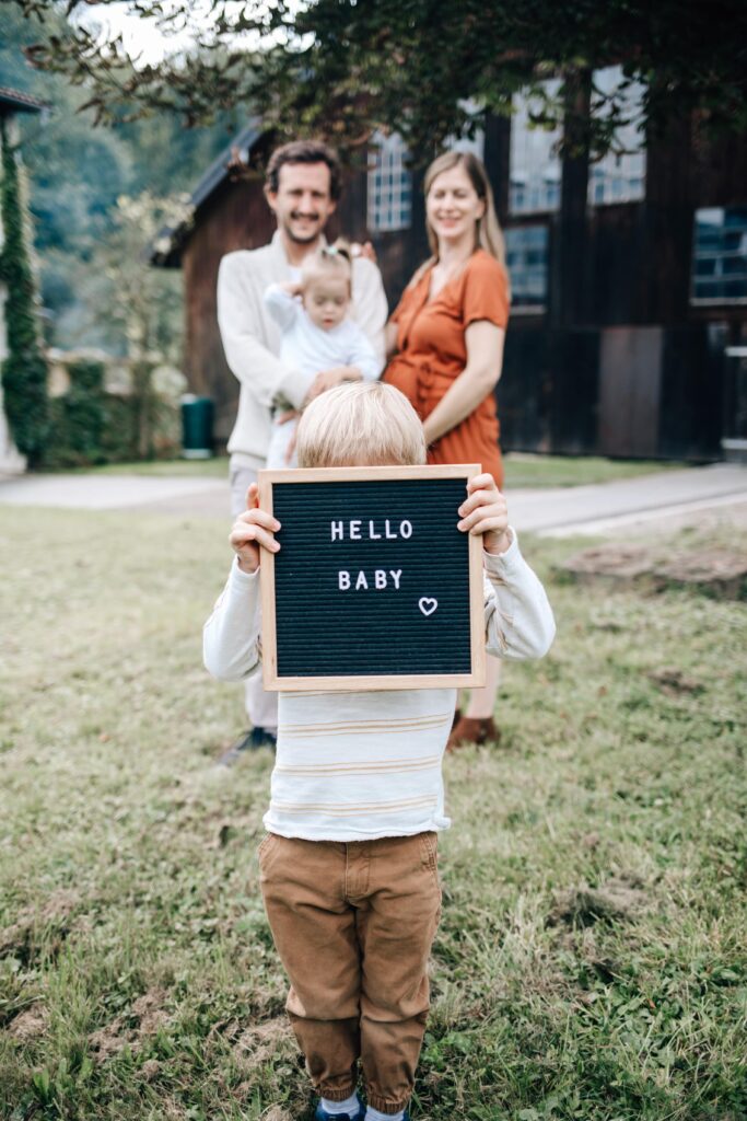 kind haelt baby schild hoch bei babybauchshooting mit fotografin in sinsheim