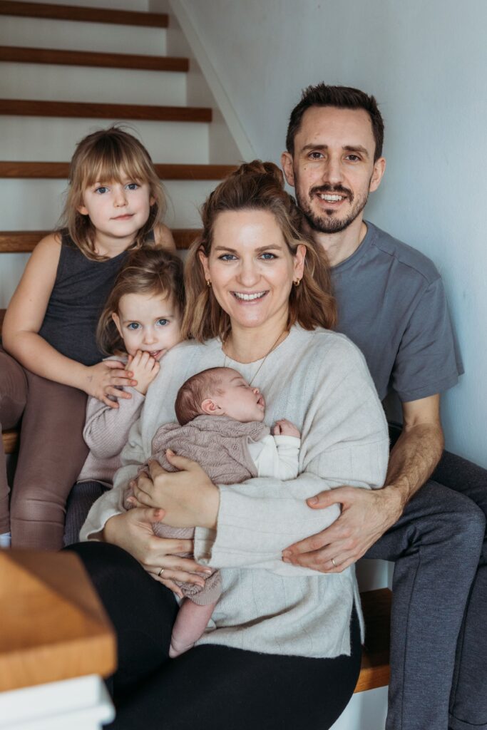 Familie sitzt auf der Treppe und lacht in die kamera